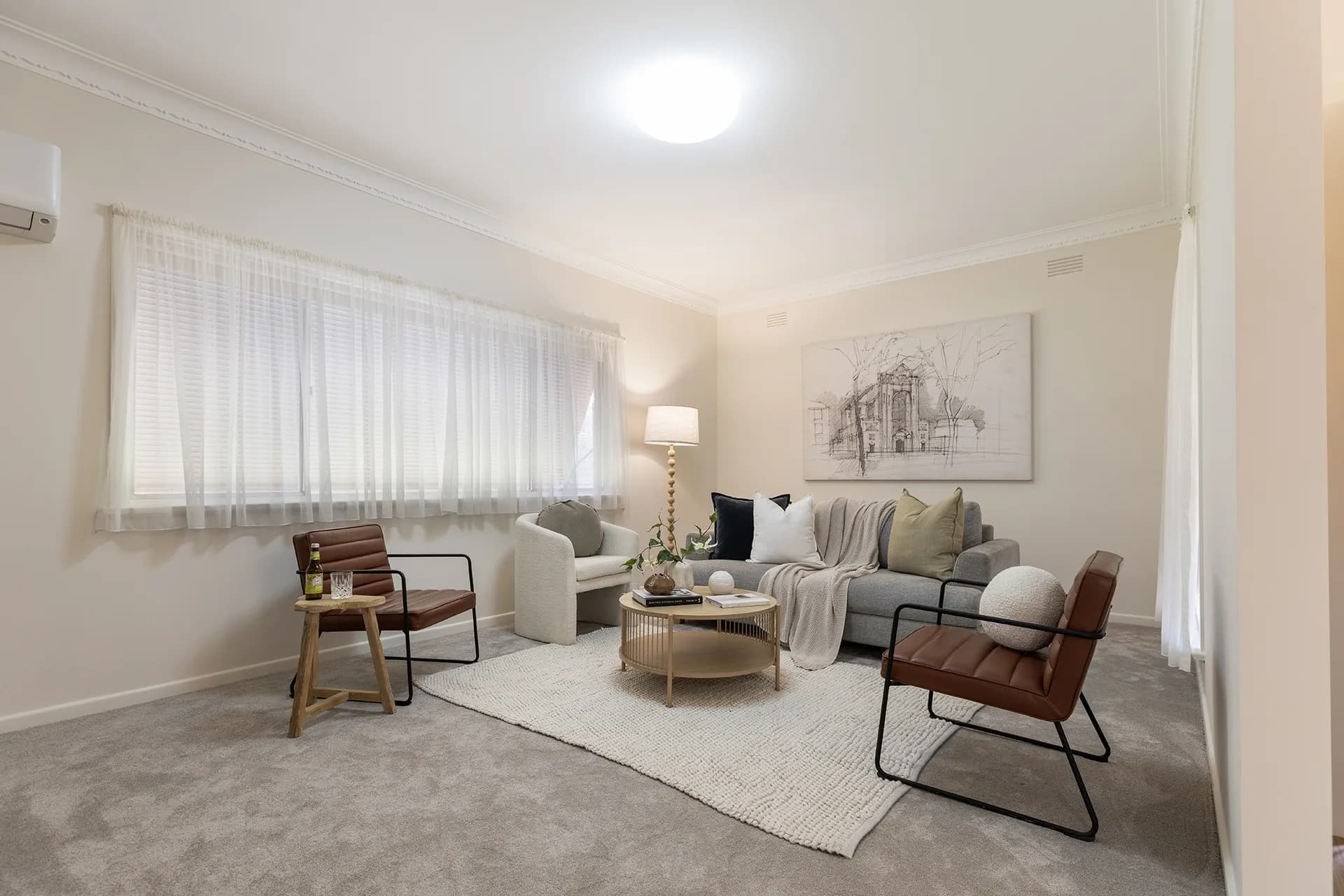 Living room with a grey sofa, leather armchairs and a round timber coffee table at Corrigan Avenue, Kyabram